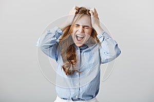 Cannot handle pressure anymore. Tensed fed up european female model in blue-collar shirt, yelling or screaming while