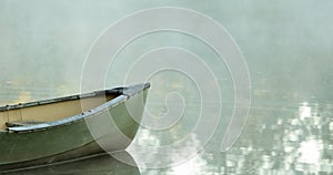 Canoe on glassy water with fog, negative space for text.