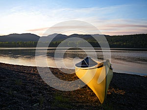 Canoe on lake shore at dusk.