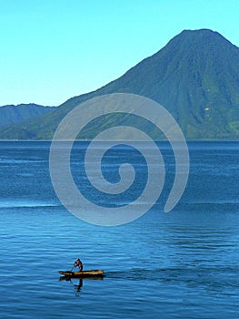 Canoe with lone boatman Lake Atitlan with Toliman volcano, Guatemala