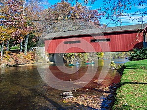 Canoe Trip Passing Underneath Old Covered Bridge On Sunny Autumn Day