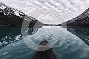 Canoeing with cloudy reflection on Maligne Lake in Rocky Mountains at Jasper national park