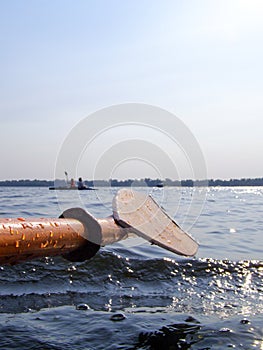 Canoeing. Wooden Paddle from a kayak over the water. People rowing in a canoe on the river