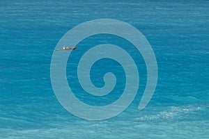 A canoeist floating in turquoise sea, view from faraway. Holidays, outdoor sport activity. .