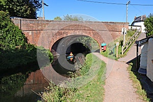 A canoeist paddles under a canal bridge at Sampford Peverell on the Grand Western canal in Devon