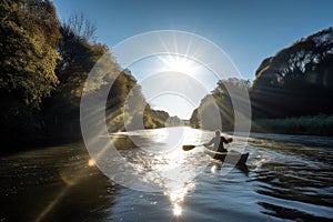 canoeist paddling down a tranquil river, with the sun shining overhead