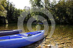 Canoes on the bank of a beautiful river with a background of trees and kayaks descending the river. sport and nature