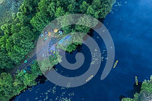 Canoes on the calm river and camp on the bank of the river. Aerial top view. Beautiful picture of river and green banks of the