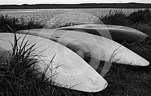 Canoes Laying Upside Down On Bank Of A Lake in Black And White