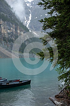 Canoes in turquoise Lake Louise with misty mountains in the background