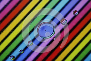 Canola oil and water drops on a transparent surface with colored streaks by reflection photo