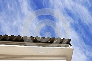 canopy roof of the house with a wavy roofing material on background blue sky clouds in summer