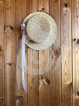 Canotier hat with a white ribbon on a wooden background