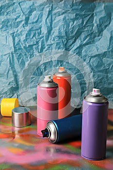 Cans of different graffiti spray paints on color background