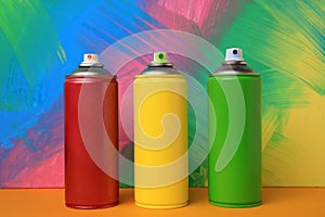 Cans of different spray paints on color background. Graffiti supplies