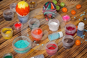 Cans of paint, glitters, painted easter eggs, candies on wood