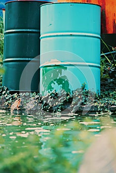 cans and toxic metal barrels abandoned in nature polluting the water of lakes and rivers