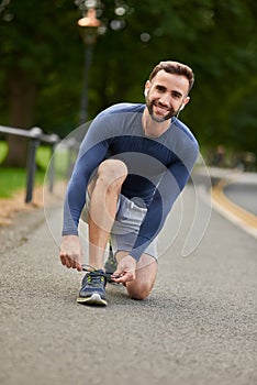 Cant afford to stumble. Full length portrait of a handsome young male runner tying his shoelaces during an outdoor