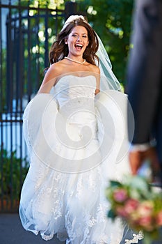 She cant get to him fast enough. Fun full length shot of a new bride running happily through church grounds.