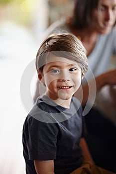 Cant wait till my friends get here. A young boy smiling happily as he sits at home.