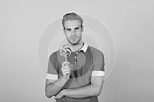 Cant wait to get a bite of lollipop. Young guy hold lollipop yellow background. Eating lollipop. Large swirl lollipop on