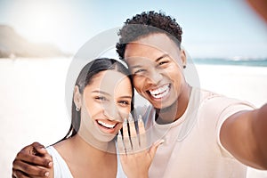 We cant wait to tell everyone. a newly engaged couple taking a selfie together at the beach.