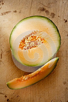 Cantaloupe melon slice and one half on wood