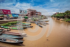 Inle Boat Station in Inle Nyaung Shwe Canal. A series of fishing boats along the river generated by Inle Lake. Homes in the backgr