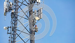 Communication maintenance. Technician climbing on telecom tower against blue sky background