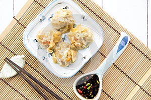 Cantonese Dimsum food cuisine . Fresh  prawn wrapped in yellow dumplings, Steamed Chinese wrapped in yellow Dumplings.White wood f