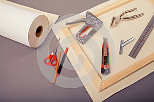 Canvas artist on roll, stretcher for canvas, staple gun and other tools on a gray background