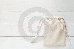 Canvas bag with drawstring, mockup of small eco sack made from natural cotton fabric cloth flat lay on white wood background from