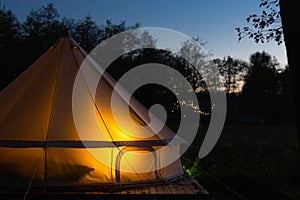Canvas glamping tent glows at night