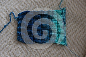 The canvas is knitted from melange yarn with knitting needles. The knit and purl stitches alternate in the pattern.