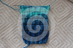 The canvas is knitted from melange yarn with knitting needles. The knit and purl stitches alternate in the pattern.