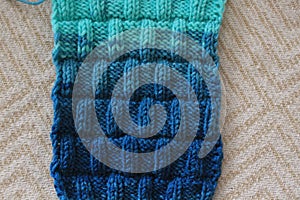 The canvas is knitted from melange yarn with knitting needles. The knit and purl stitches alternate in the pattern.