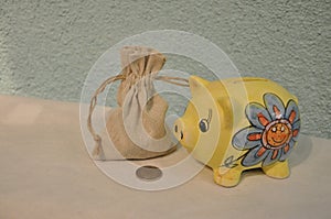 Bag full of money and yellow piggy bank or money box  over blue wooden background.