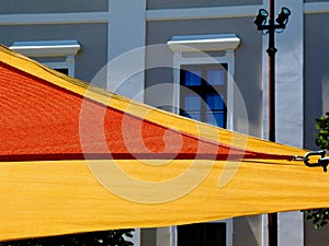 canvas patio awning. colorful sun shade sail UV protection fabric suspended from exterior walls.