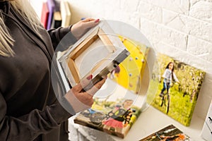 Canvas print. Photo of canvas stretching on stretcher bar. Woman hangs a color travel photography