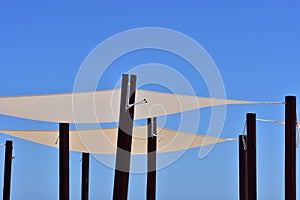 Canvas shades on black poles against the blue sky