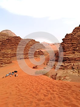 View from the dune of the red earth valley of Wadi Rum with the background of tourists photo