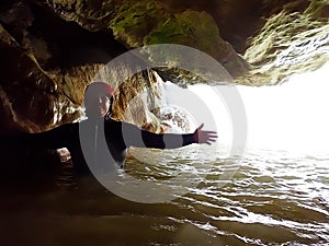 Canyoning, extreme sports. A happy man in a cave's water.