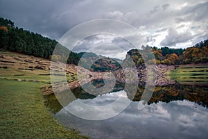 The canyoning of the Mino river near Portomarin is reflected in the calm waters of the river