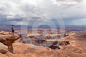 Canyonlands - Man with scenic view on Split Mountain Canyon seen from Grand View Point Overlook near Moab, Utah, USA