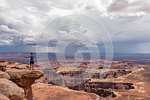 Canyonlands - Man with scenic view on Split Mountain Canyon seen from Grand View Point Overlook near Moab, Utah, USA