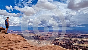 Canyonlands - Man with scenic view on Split Mountain Canyon seen from Grand View Point Overlook near Moab, Utah, USA