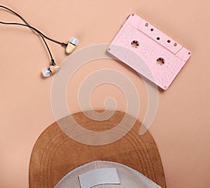 Cap, audio casset earphones on a brown background, music lover, minimalism, top view.