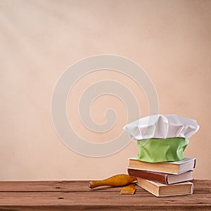 Cap chef, cookbook and kitchenware on beige vintage background