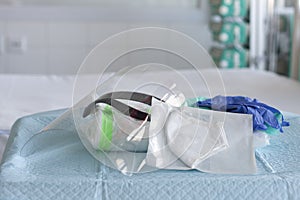 Cap, pair of gloves, plastic protective face shield , respirator ffp2 and coverall clothing  on table in ICU in hospital, personal