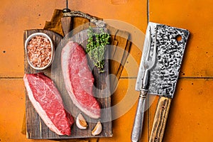 Cap Rump steak, raw beef meat steak with thyme and salt on wooden butcher board. Orange background. Top view